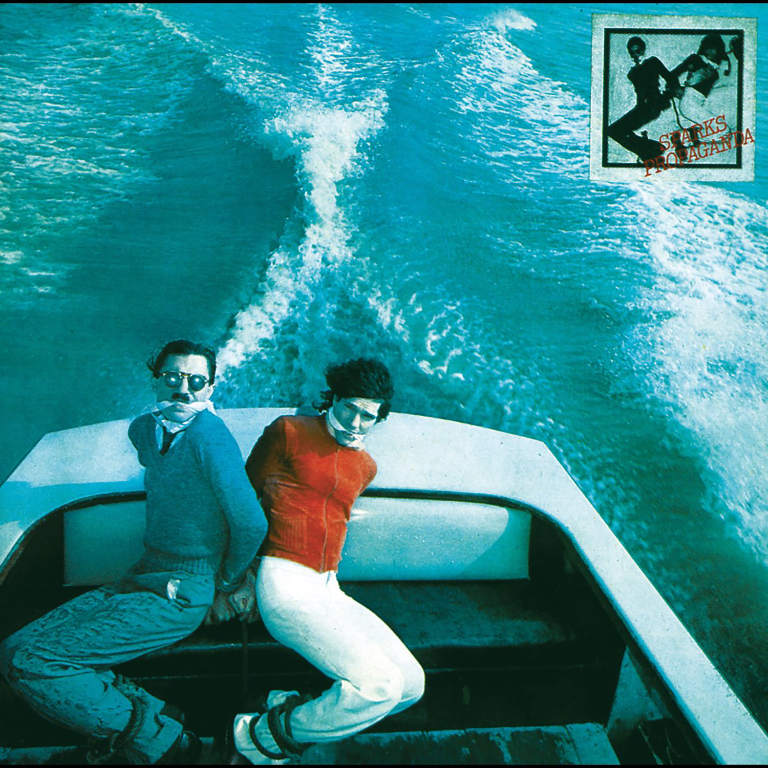 Speedboat with two people sitting in it, leaving a wake in turquoise water.